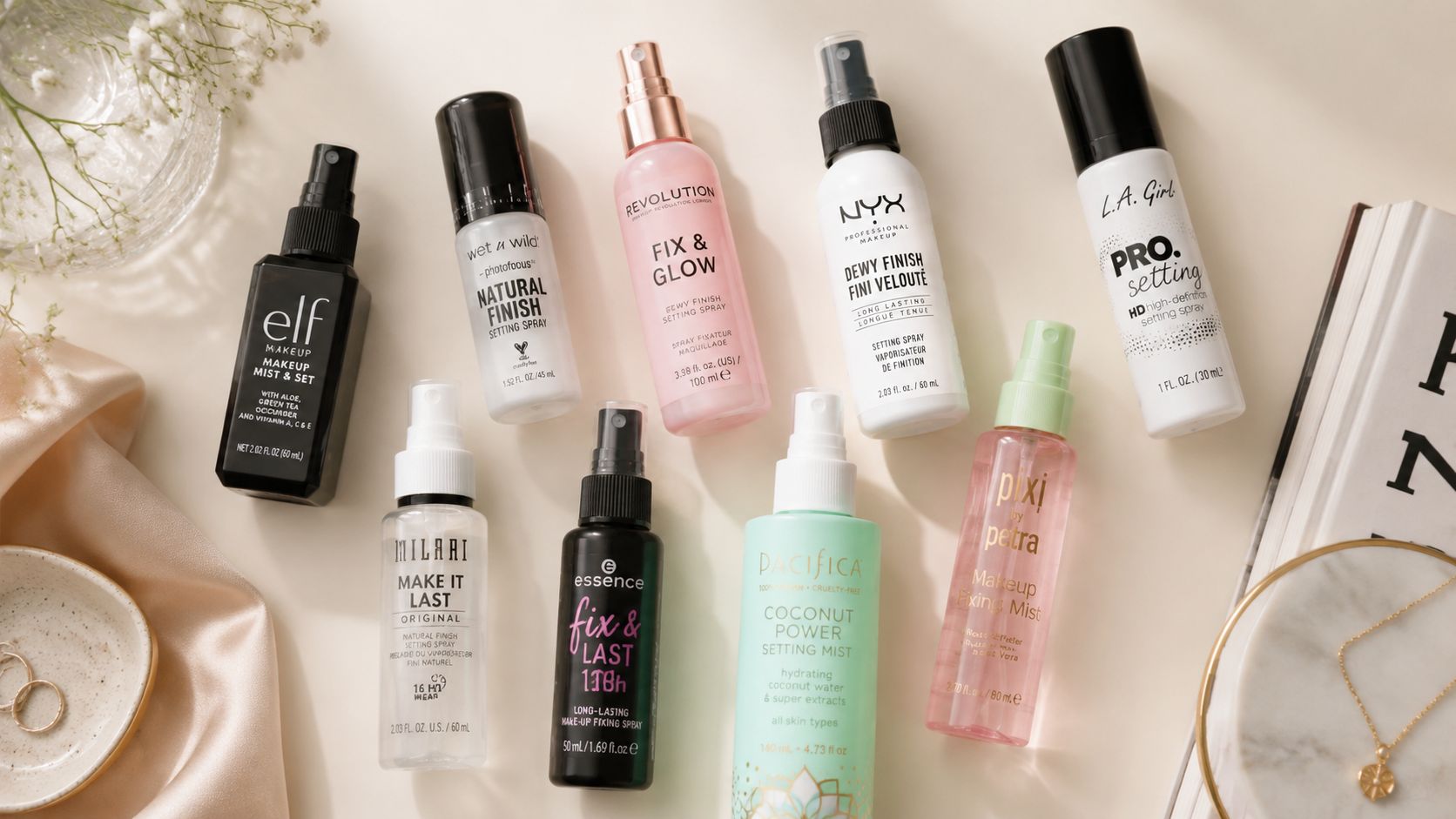 An aesthetic top-down view of several popular affordable makeup setting sprays arranged on a flat surface.