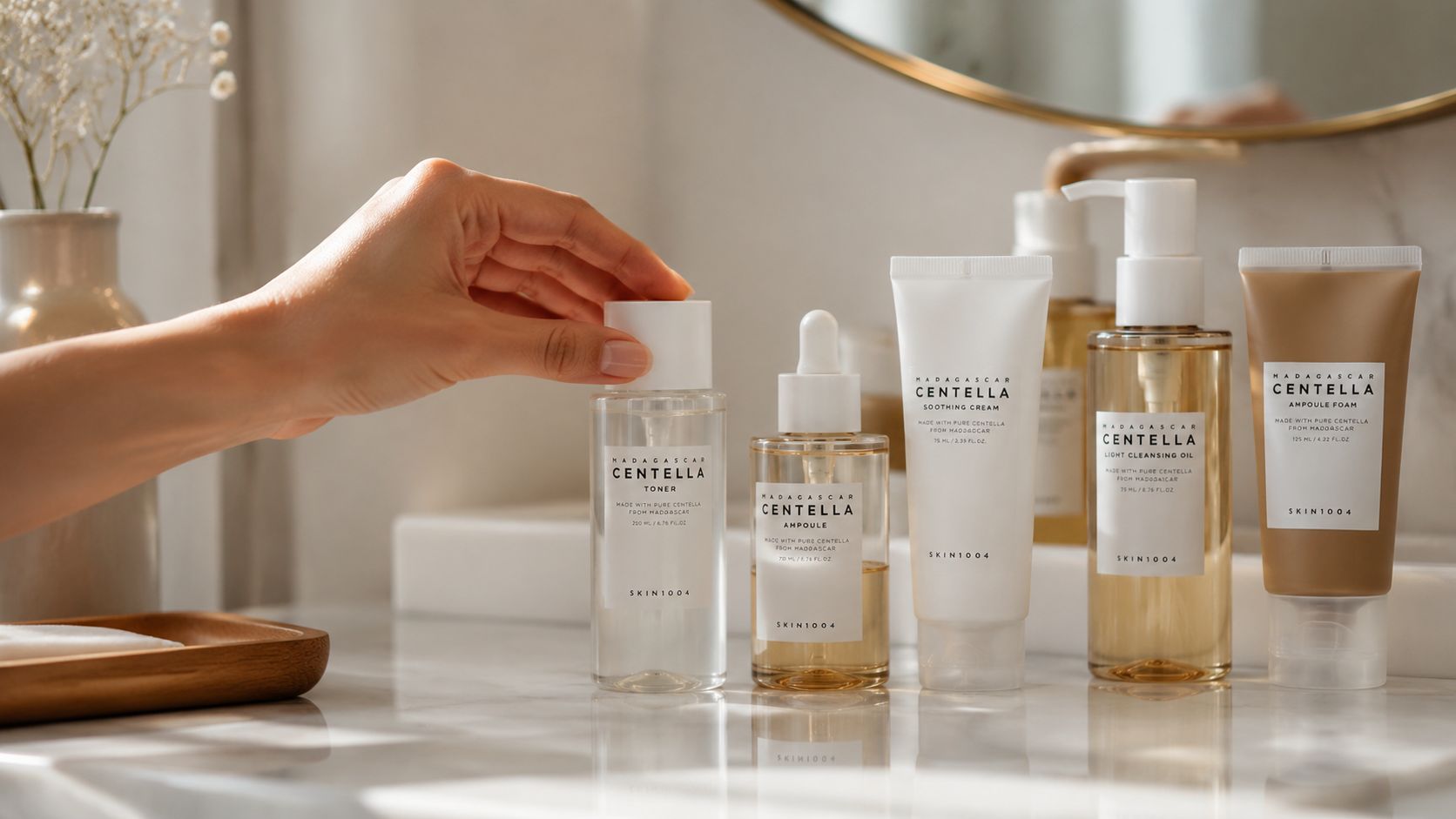 A hand reaching for a bottle of SKIN1004 Madagascar Centella Toner on a white marble vanity countertop.