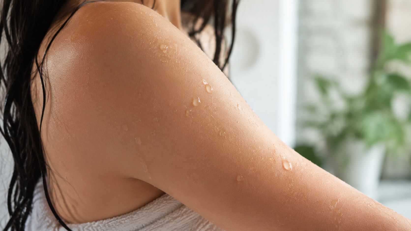 A close up view of a woman's shoulder and upper arm with water droplets after showering