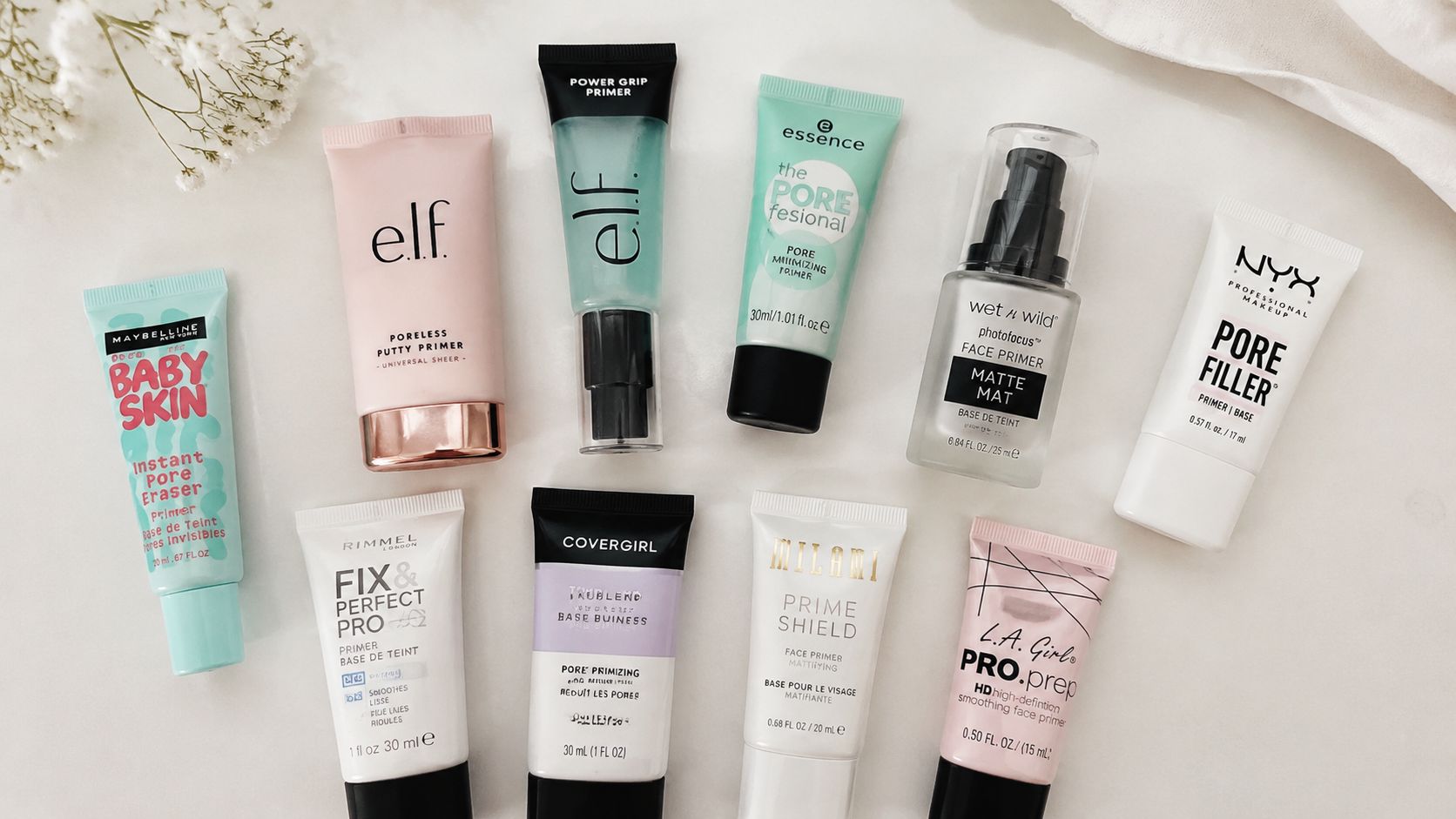 A collection of various affordable makeup primer tubes and bottles arranged neatly on a white surface.