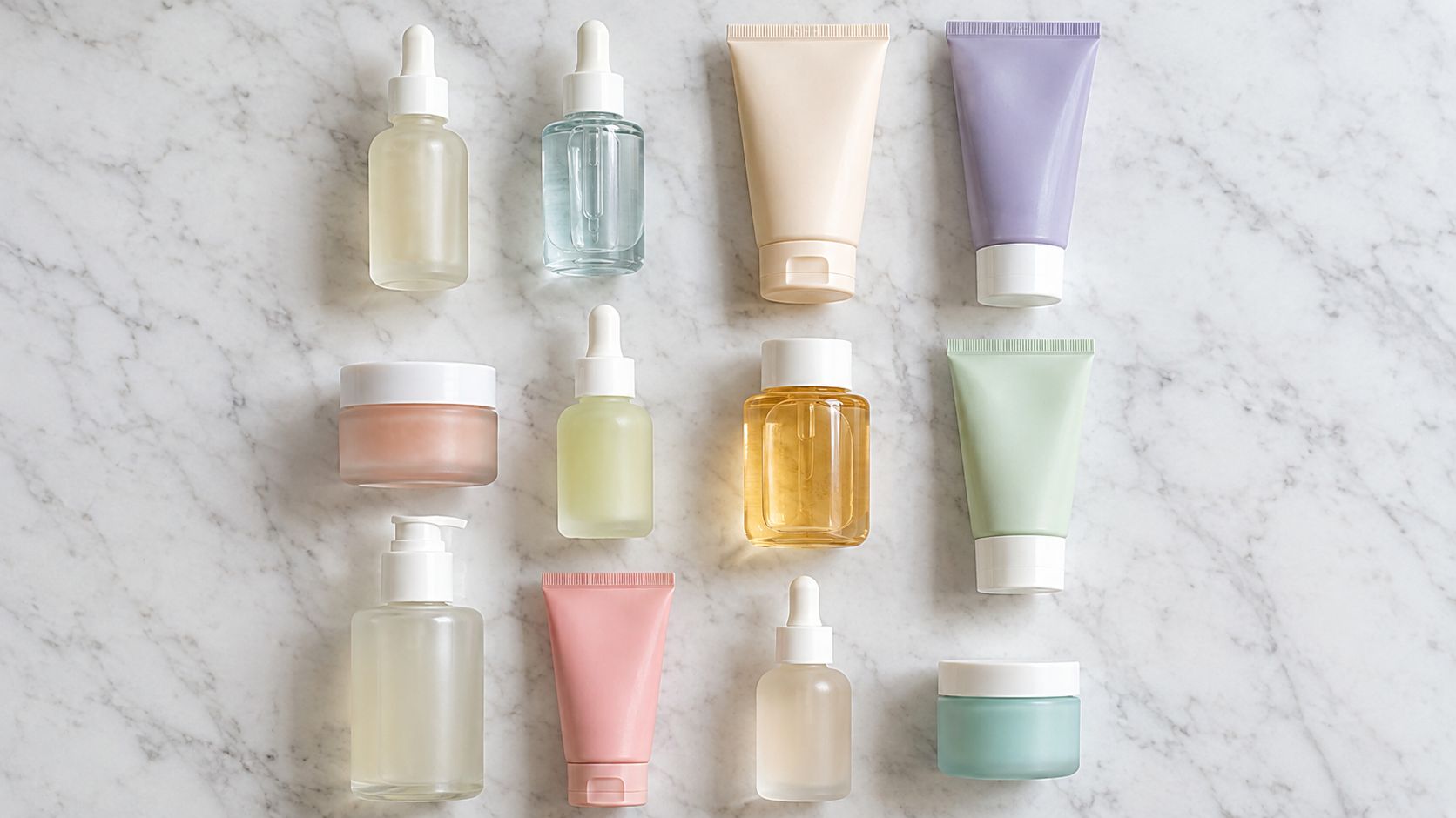 An aesthetic flatlay of various skincare serum bottles, cream jars, and tubes on a marble surface.