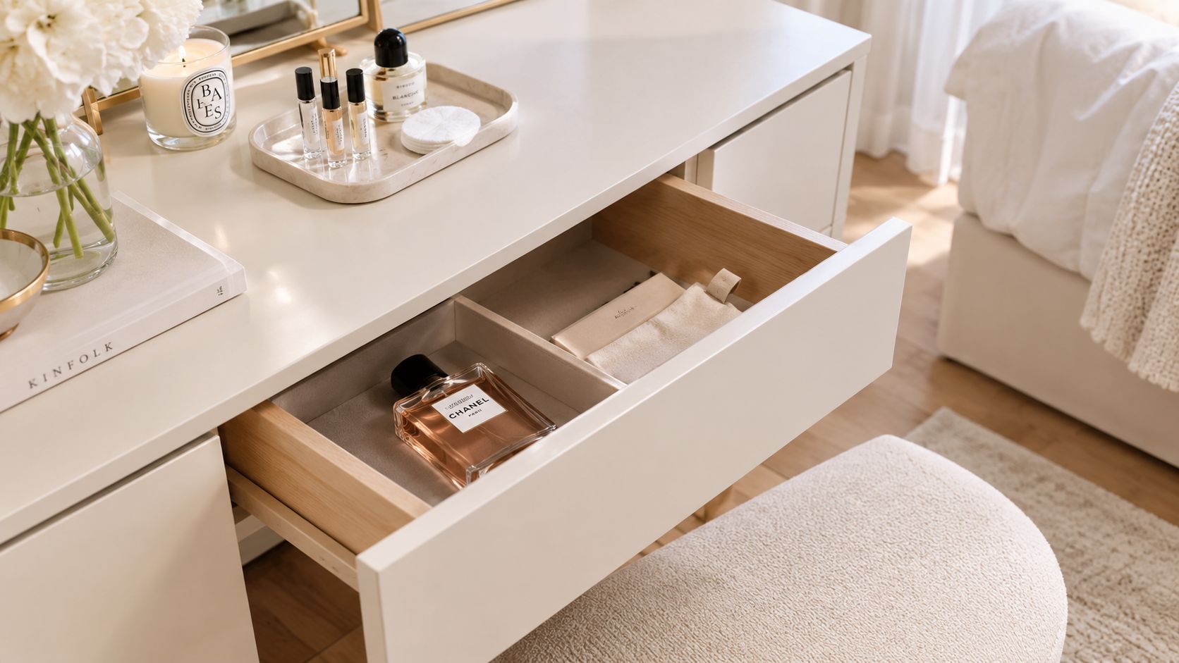 A minimalist vanity table featuring a Chanel perfume bottle inside an open drawer and beauty products above.
