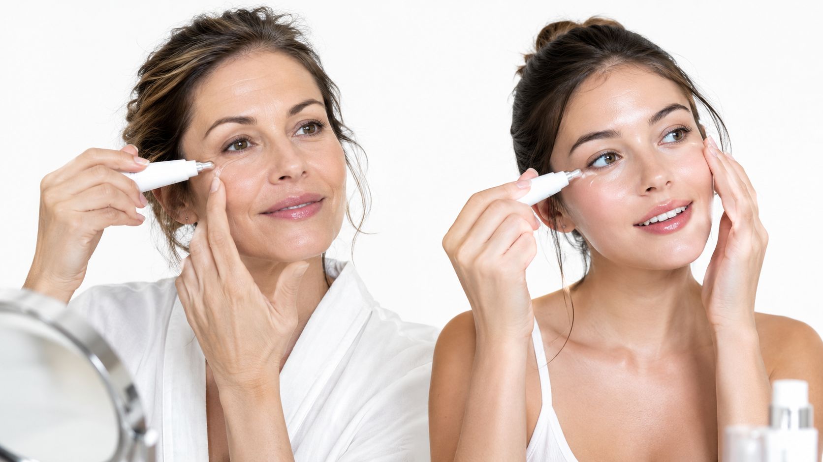 A mature woman and a younger woman applying eye cream under their eyes using an applicator tool.