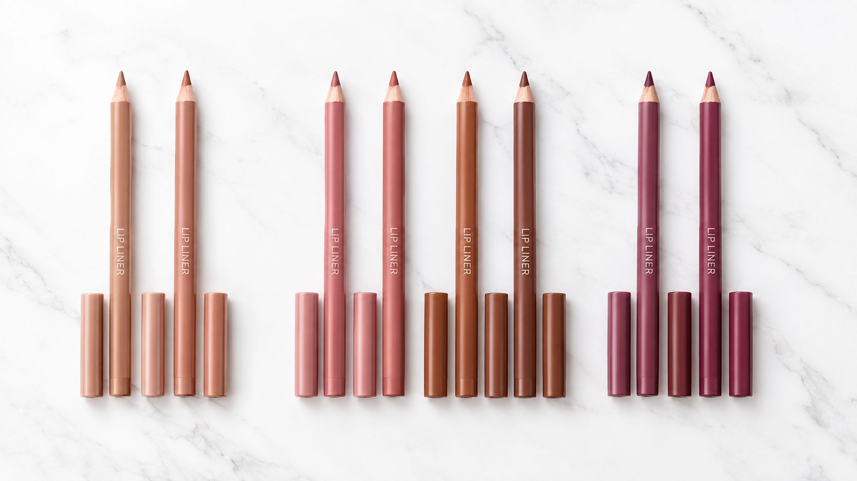 A collection of assorted lip liner pencils arranged in rows on a white marble background.