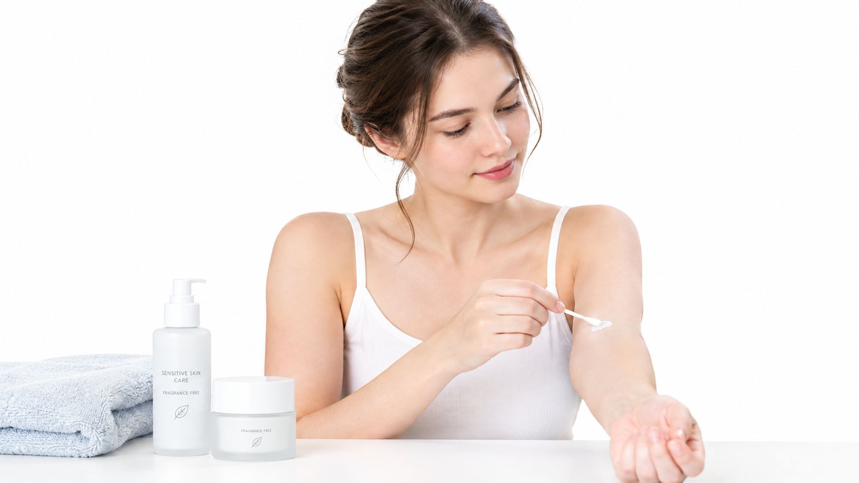 A young woman applying a gentle skincare product on her arm with a cotton swab.