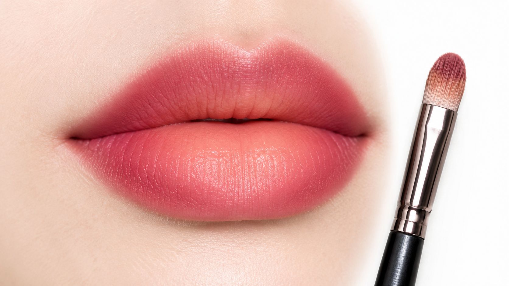 Close-up of perfectly applied gradient pink lipstick on soft lips next to a makeup application brush