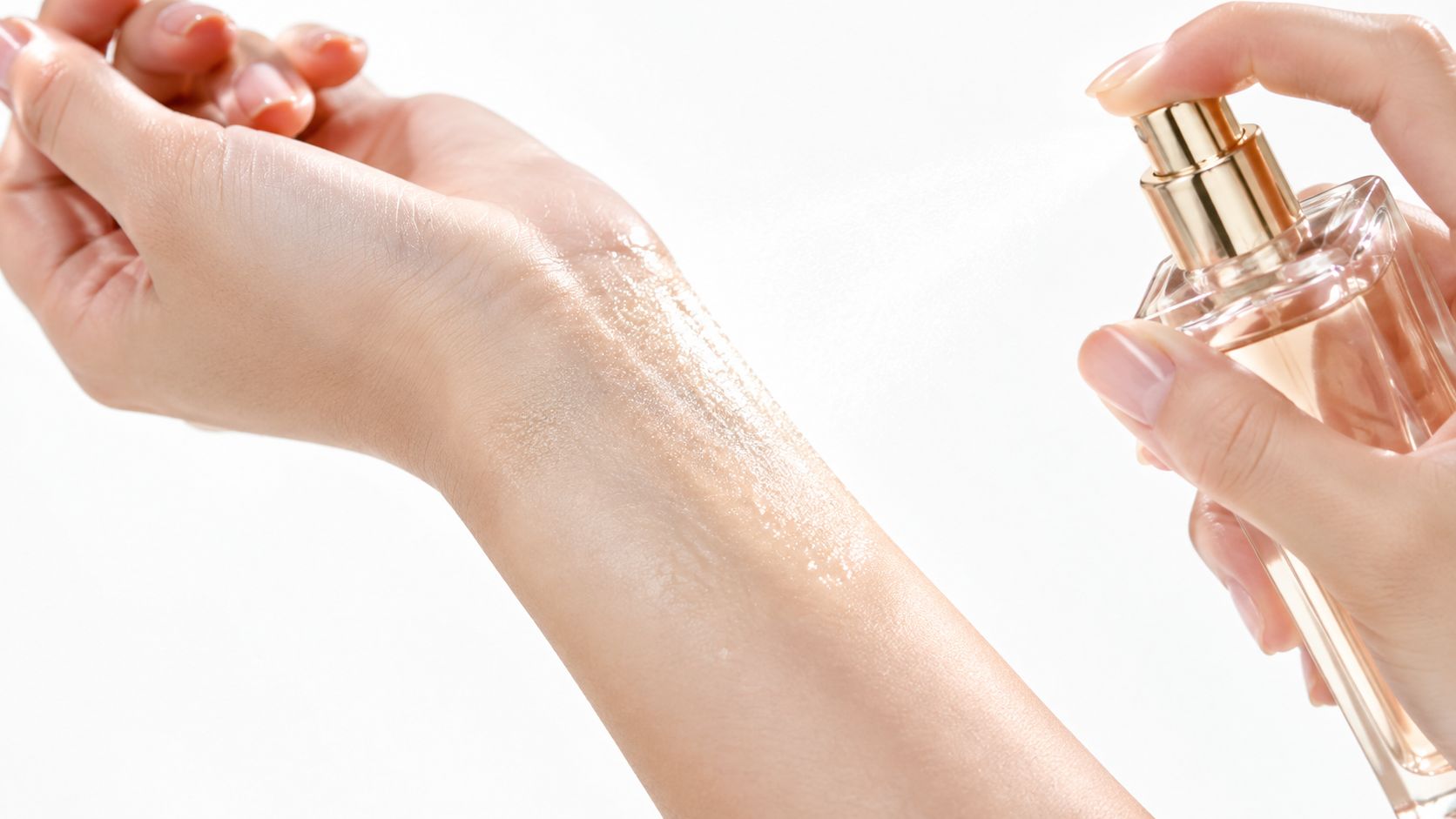 A close-up of a person spraying perfume onto their inner wrist against a clean white background.